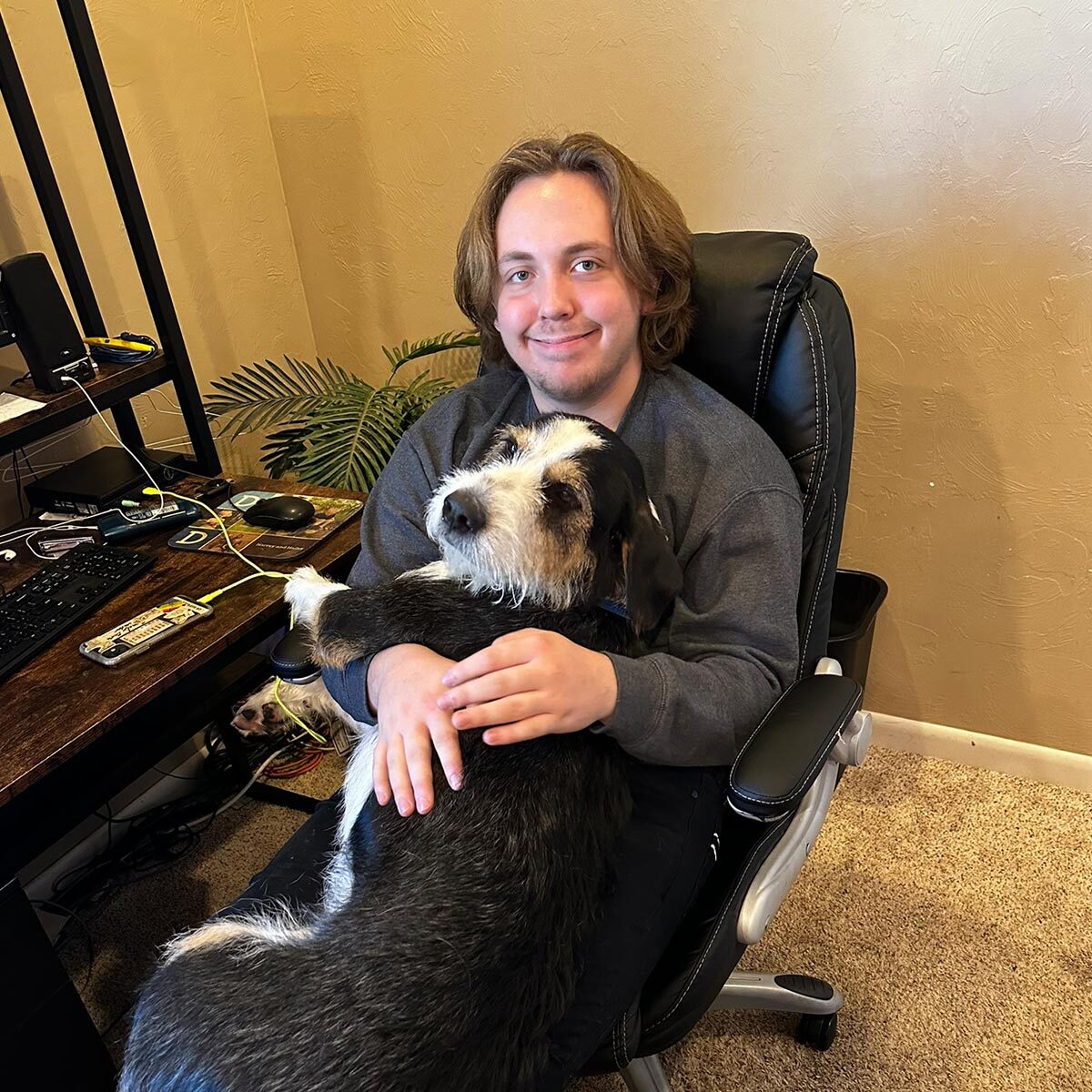 male staff member smiling and holding medium sized dog in lap